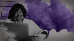 A Smiling Woman of Color With a Laptop and a Cup of Coffee